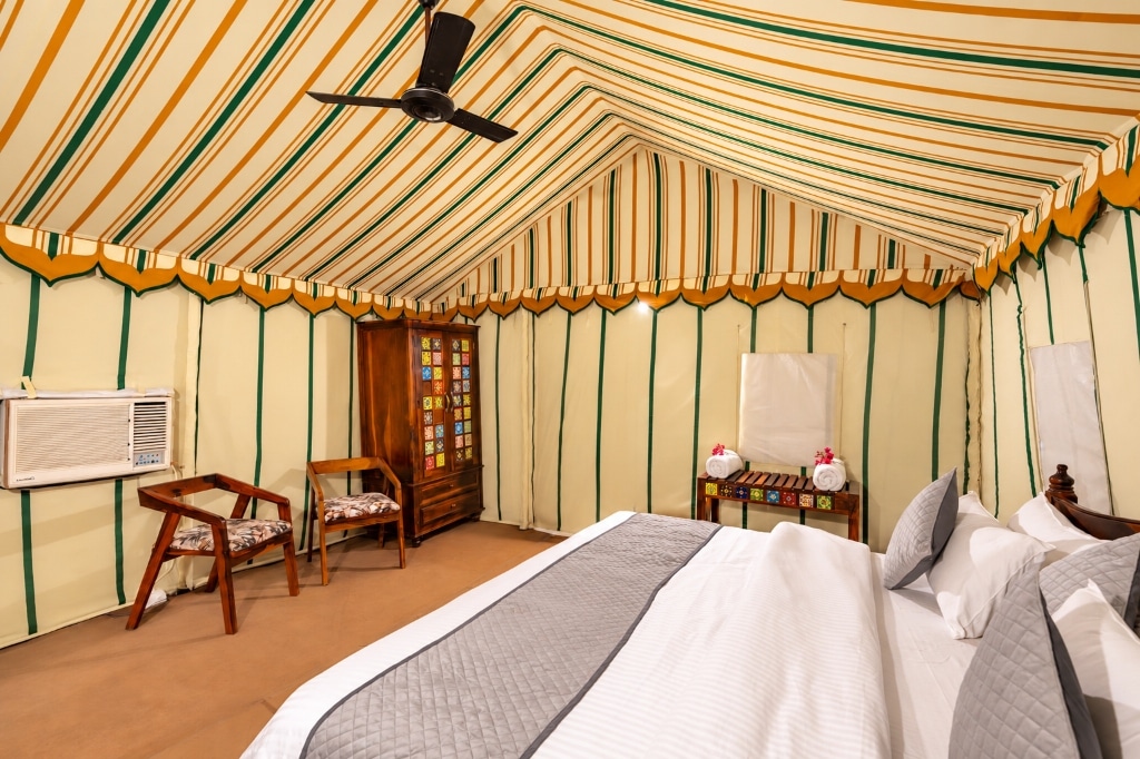 Luxury royal canvas tent suite at RETIVAA DESERT CAMP with plush king bed, striped canopy, and air conditioning